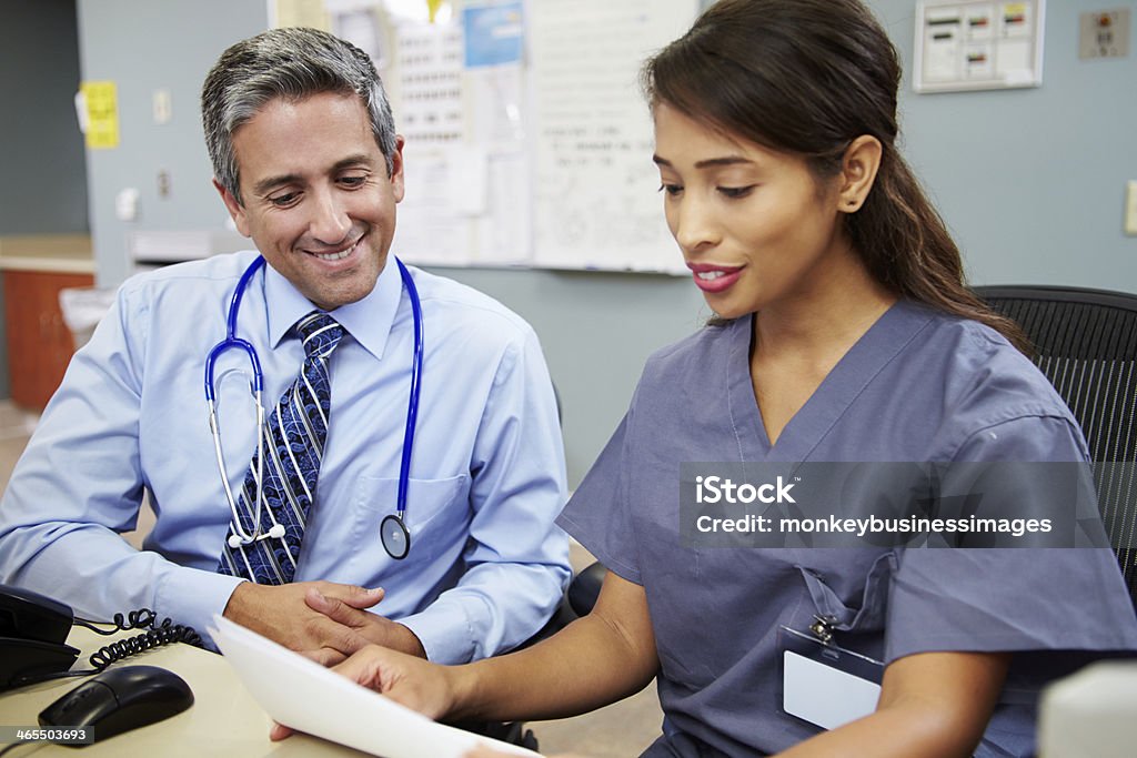 Doctor With Nurse Working At Nurses Station Happy Smiling Doctor With Nurse Working At Nurses Station Latin American and Hispanic Ethnicity Stock Photo