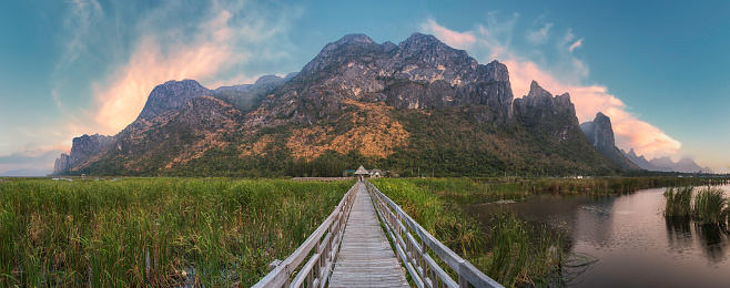 A dramatic freshwater wetland scene in central Thailand, with a backdrop of large limestone hills. The place name translates as 'Mountain of 300 Peaks'.