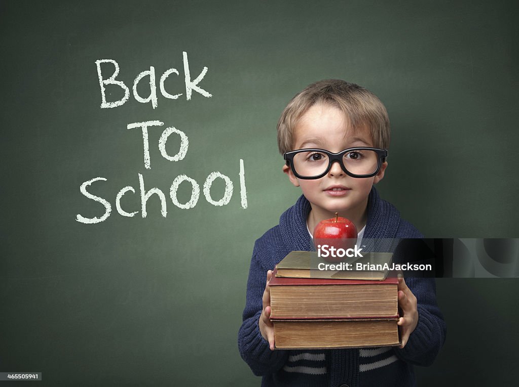 Back to school Young child holding stack of books and back to school written on chalk blackboard Back to School Stock Photo