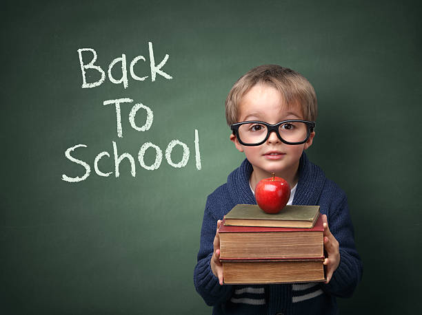Back to school Young child holding stack of books and back to school written on chalk blackboard chalk art equipment photos stock pictures, royalty-free photos & images