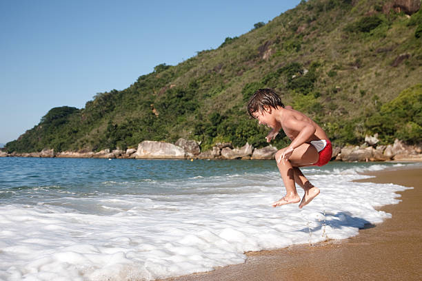 Four year old jumping the waves on the beach.