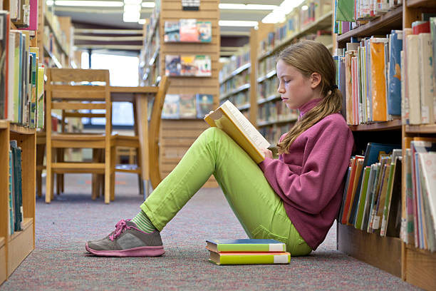 istock Young girl reading book at library 465509331