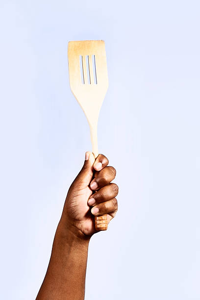 istock Single hand holds multi-purpose wooden kitchen utensil aloft 465509383