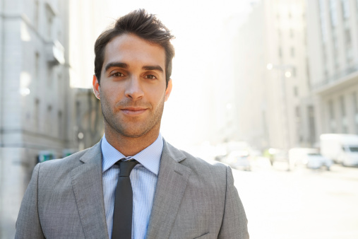 A satisfied and handsome businessman standing out in the city