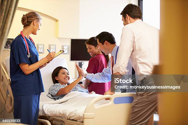 Medical Team Meeting Around Female Patient In Hospital Room Stock Photo - Download Image Now