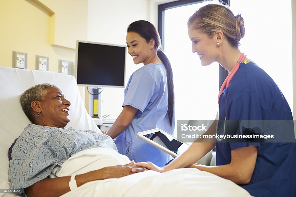 Enfermera hablando con comprimido a senior mujer - Foto de stock de Personal de enfermería libre de derechos