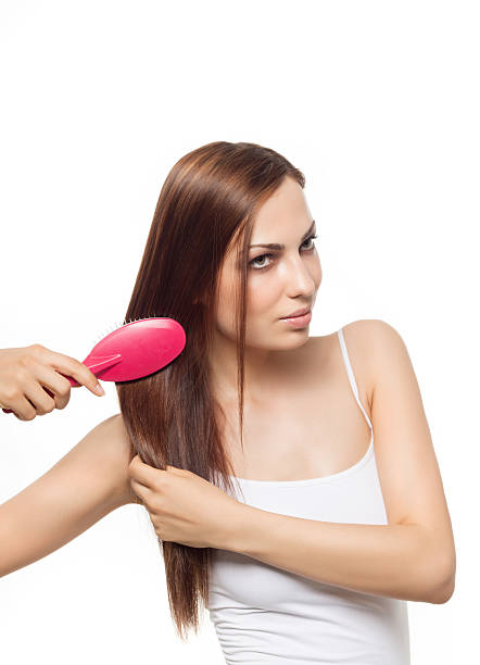 beauty portrait of attractive smiling young caucasian woman brunette long hair brushing her hear red comb isolated on white background studio shot