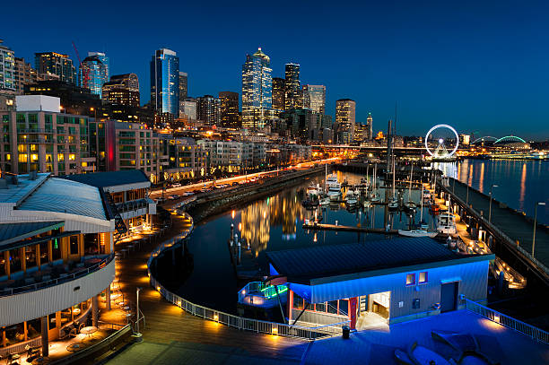 Seattle Waterfront at Sunset The Seattle, Washington waterfront and skyline at sunset with a marina and ferris wheel. The Port of Seattle can be seen in the background. elliott bay photos stock pictures, royalty-free photos & images