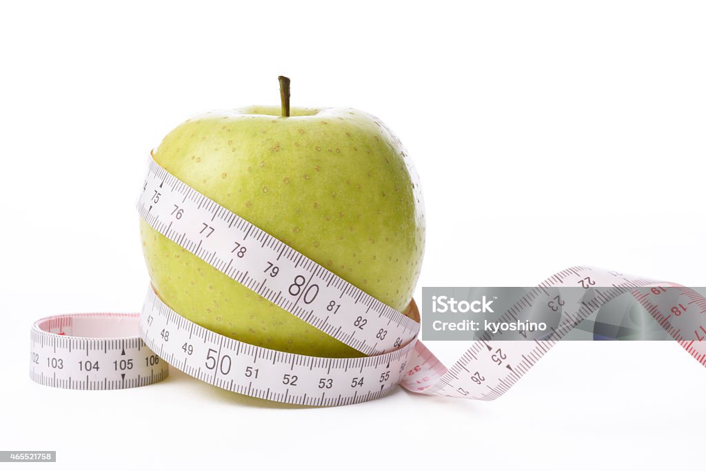 Isolated shot of apple with measurement tape on white background Green apple with measurement tape on white background with clipping path. 2015 Stock Photo