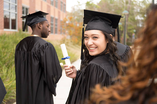 istock Education: Mixed race graduate and friends on college campus. 465523769