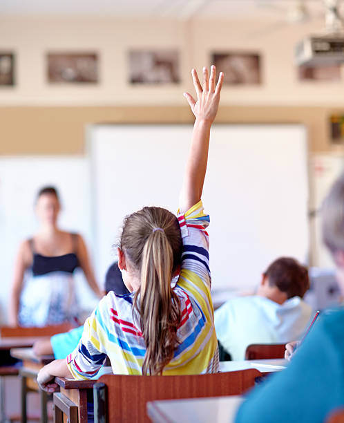 Raising her hand... A young school girl raising her hand to ask a question 12 13 years pre adolescent child female blond hair stock pictures, royalty-free photos & images