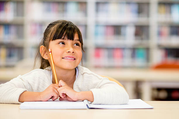 Female student thinking Young female student thinking at the library schoolgirl stock pictures, royalty-free photos & images