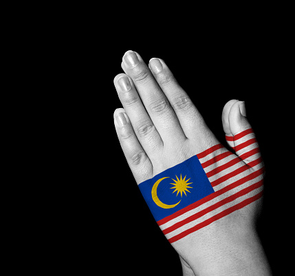 Hands folded in prayer - Malaysia flag painted on hands - Digitally generated