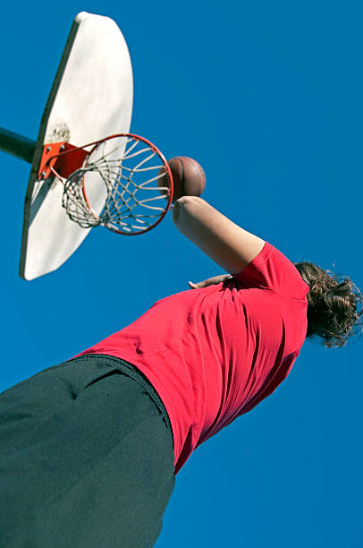 istock Young woman shooting basketball at park 465530009