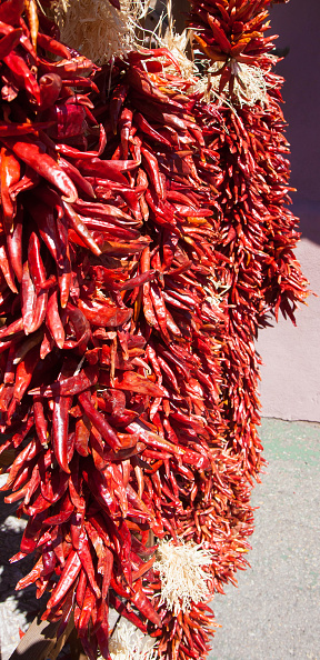 Hanging Chile Pepper Ristras in Santa Fe, New Mexico souvenir street market. A ristra is an arrangement of drying chili pepper pods. Ristras historically served as a functional system of drying chile for later consumption. Today, ristras are commonly used as a trademark of decorative design in the state of New Mexico, however, many households still use ristras as a means to dry and procure red chile.