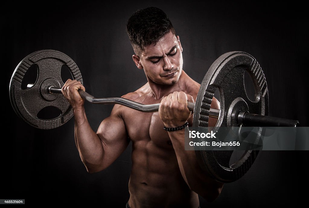 Body Building In Progress Body builder performing barbell curls exercise. 2015 Stock Photo