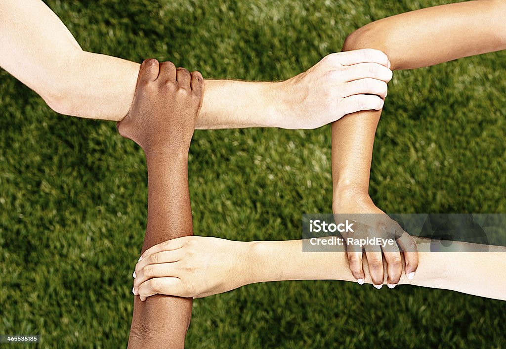 Interracial Гармония: Различные руки с четырьмя Площадь на траве - Стоковые фото Африканская этническая группа роялти-фри