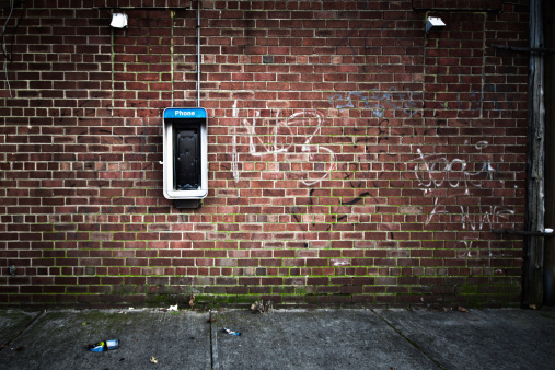 Grungy urban background of a brick wall with an old out of service payphone on it