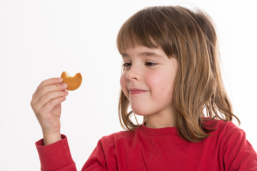 Little girl eating a cookie isolated on white background