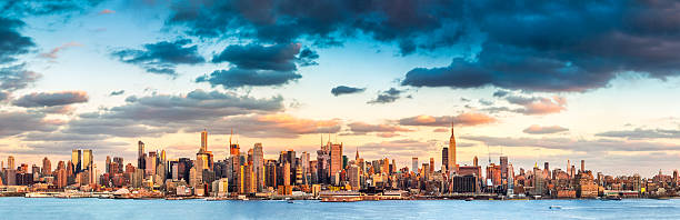 Panorama of New York City behind water with sunset clouds Panoramic view of the midtown Manhattan skyline before sunset (ultra high resolution) new jersey photos stock pictures, royalty-free photos & images