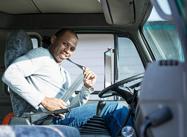 African American man driving truck African American man (30s) driving delivery truck, putting on seat belt. buckle photos stock pictures, royalty-free photos & images