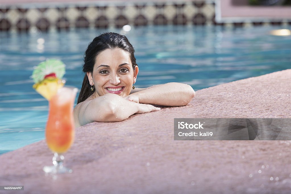 Hispanic woman with cocktail in swimming pool Young Hispanic woman (20s) relaxing in swimming pool with tropical drink. 20-29 Years Stock Photo