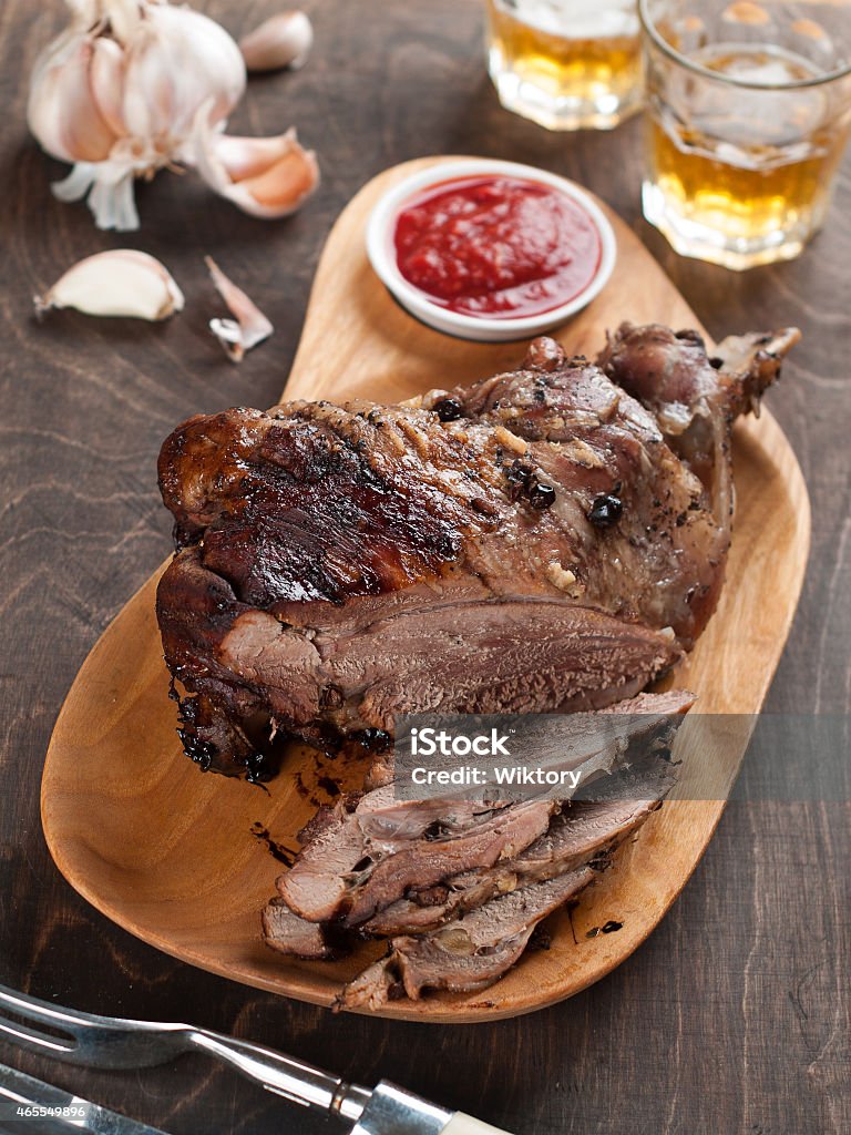 Roasted leg meat served with whiskey, sauce and garlic Roasted pork or lamb leg with sauce, selective focus Wild Boar Stock Photo