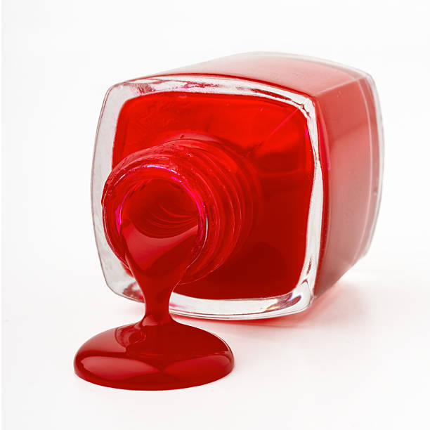 Spilling Polish Spilling Red Nail Polish on white surface. Bottle on it's side with the polish flowing into a large shinnny red droplet red nail polish stock pictures, royalty-free photos & images