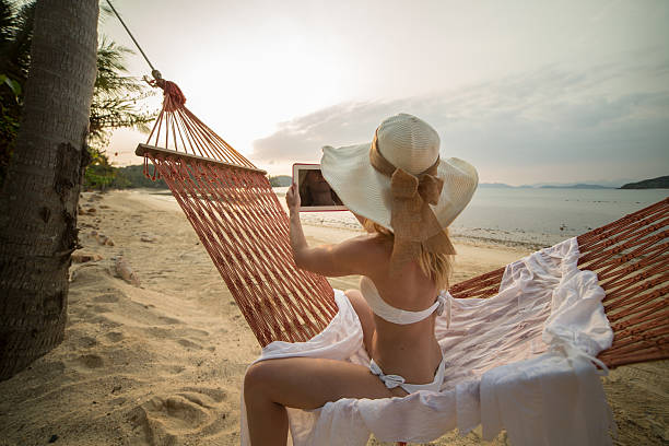 istock Young woman on hammock taking picture with digital tablet 465565148