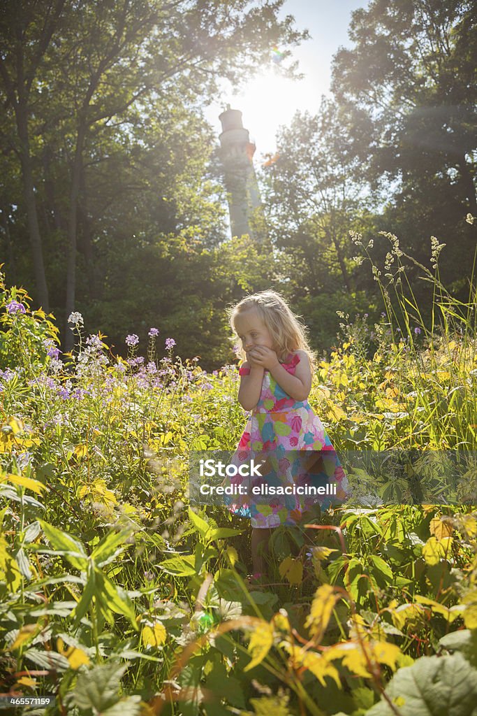 Sonriente blue eyed chica rubia de pie en un campo de flores - Foto de stock de Actividad libre de derechos