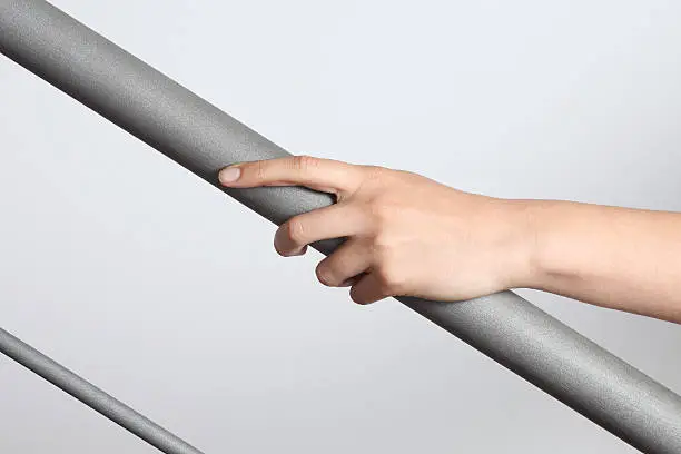 Photo of Hand holding a gray matte handrail going up, gray background