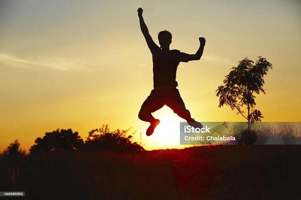 Jump Freedom and victory - young man is jumping in nature - back lit Achievement Stock Photo
