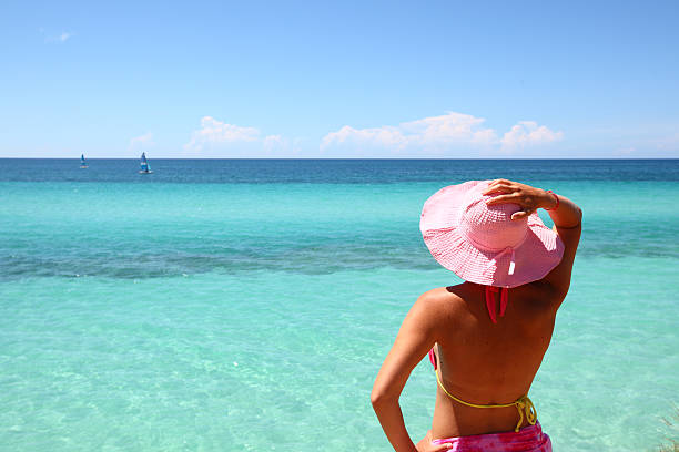 Young woman standing on the beach and looking at beautiful turquoise ocean on the Cuban beach in Varadero.