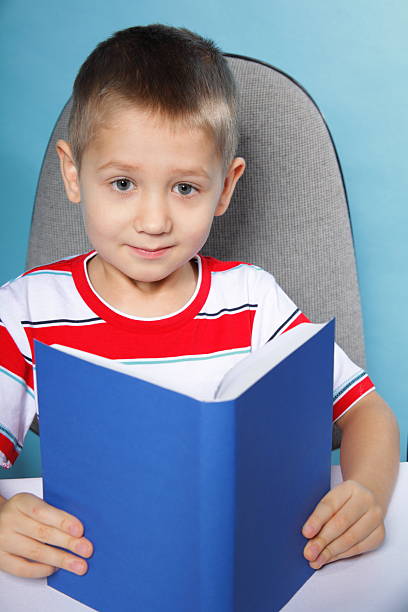 istock child boy kid reading a book on blue 465588571