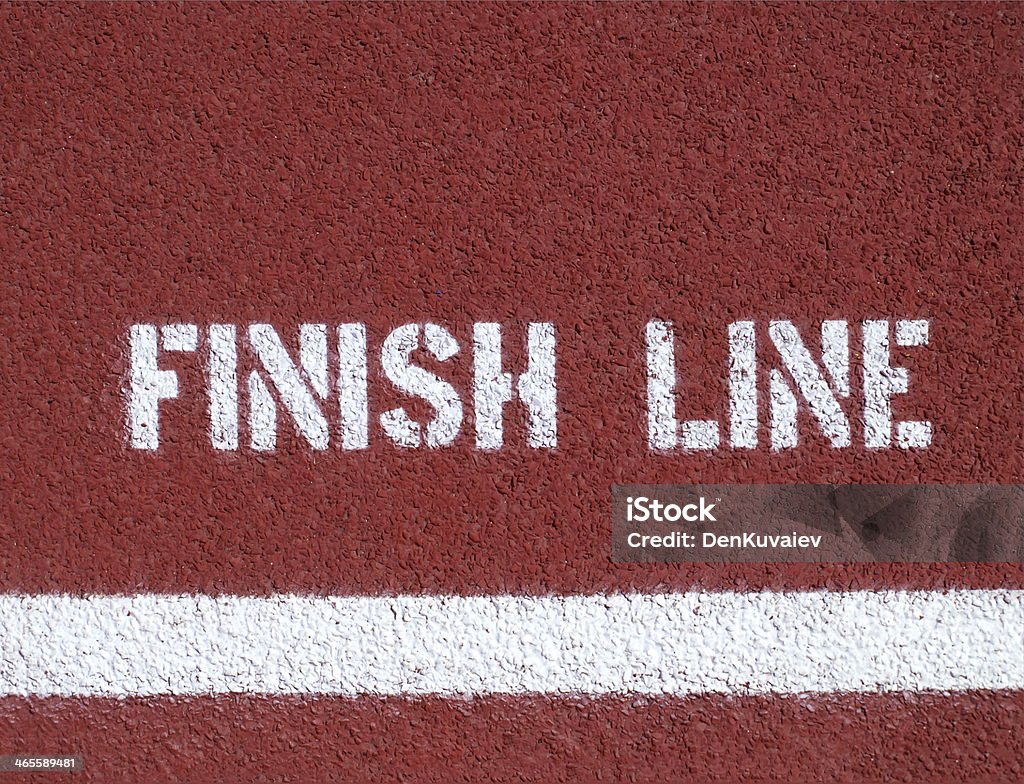 White sprayed on text over a white line on a red background Finish line - sign on the running track Finish Line Stock Photo