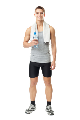 Full length portrait of young smiling muscular athlete man with a white towel on his shoulder holding a water bottle isolated on white background