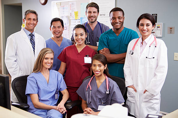 Portrait Of Medical Team At Nurses Station Portrait Of Medical Team At Nurses Station Smiling At Camera group of animals stock pictures, royalty-free photos & images