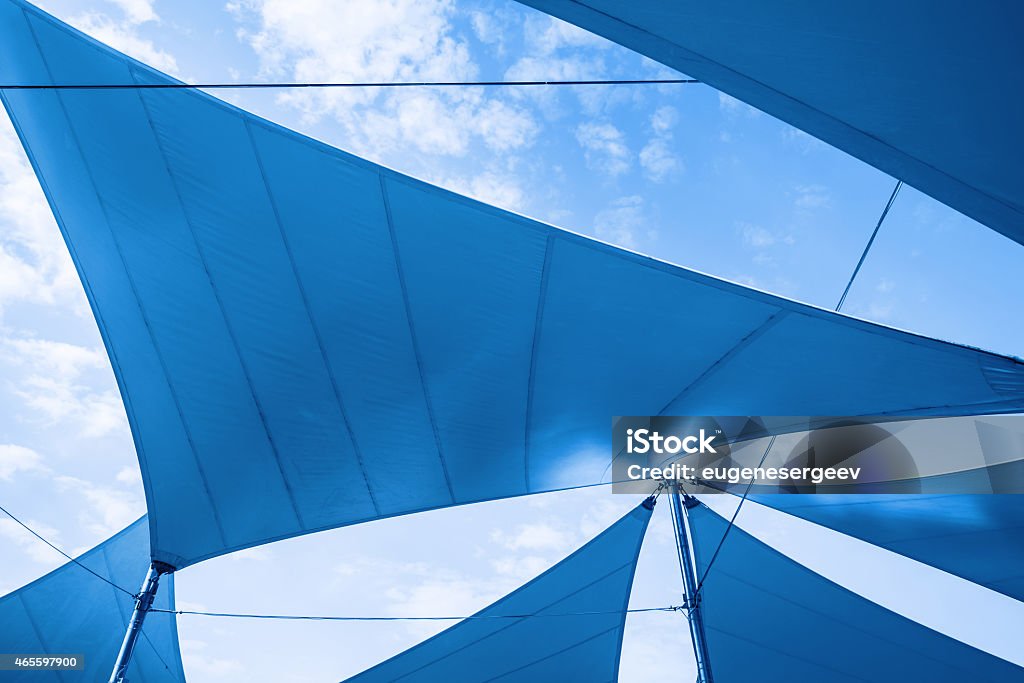 Awnings in sails shape over cloudy sky Awnings in sails shape over cloudy sky background. Blue toned photo Sail Stock Photo