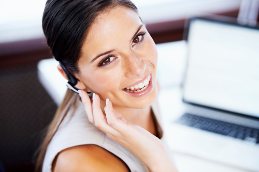 Closeup portrait of an attractive businesswomen talking on a headset while seated at her desk