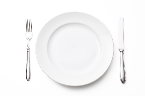 Overhead shot of white empty plate with silver knife and fork isolated on white background with clipping path.