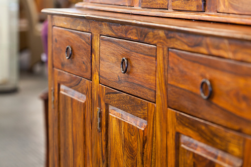 A closeup od a dark brown wooden cabinet with drawers