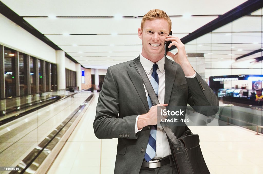 Smiling businessman on mobile in airport Smiling businessman on mobile in airporthttp://www.twodozendesign.info/i/1.png 2015 Stock Photo