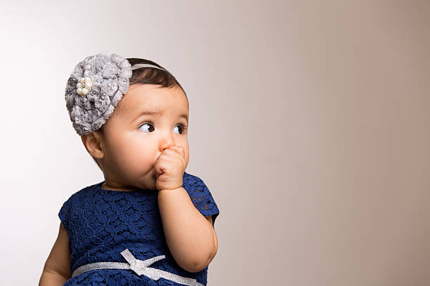 Baby girl sucking her thumb isolated over colored background
