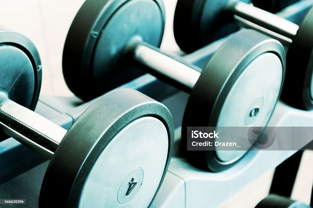 Healthy lifestyle- weights in the gym in close up image Weights in the gym in blue toned image, on the stack i n a row. Image developed from RAW file 2015 Stock Photo