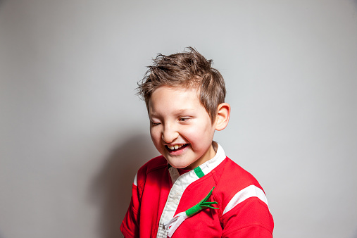 Ten year old visually impaired boy on St Davids Day in red rugby shirt and wearing a leek the traditional emblem of Wales