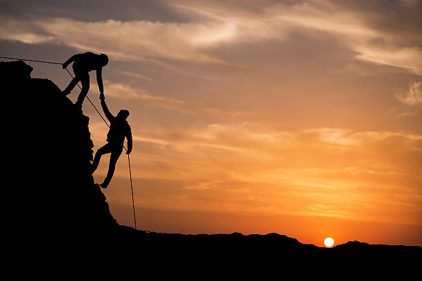 シルエットを支援の手の 2 つの凱旋 - outdoors exercising climbing motivation ストックフォトと画像