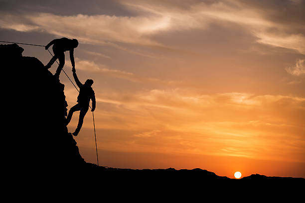 silhueta de mão entre dois alpinista ajudar - climbing clambering mountain silhouette - fotografias e filmes do acervo