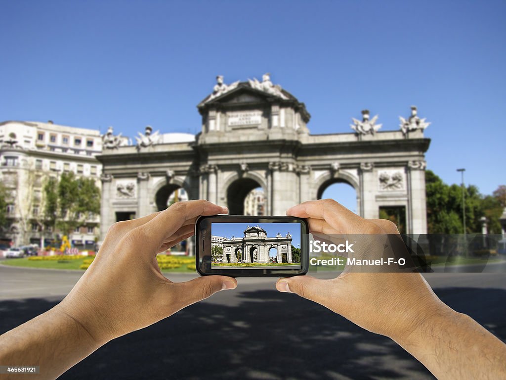 Turista tiene il cellulare con fotocamera a Puerta de Alcalá - Foto stock royalty-free di Puerta de Alcalá