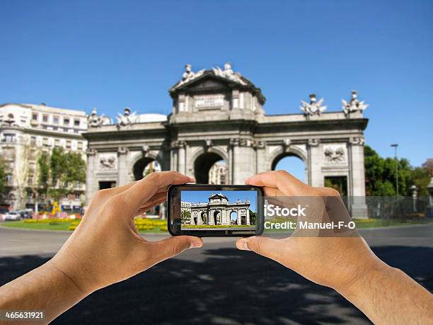 Turista Tiene Il Cellulare Con Fotocamera A Puerta De Alcalá - Fotografie stock e altre immagini di Puerta de Alcalá