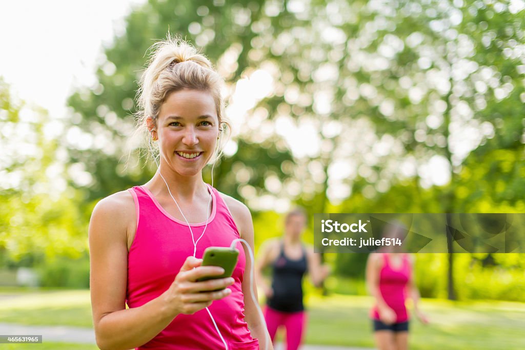 attractive blond woman listening to music Portrait of a woman using her smart phone for a workout Group Of People Stock Photo